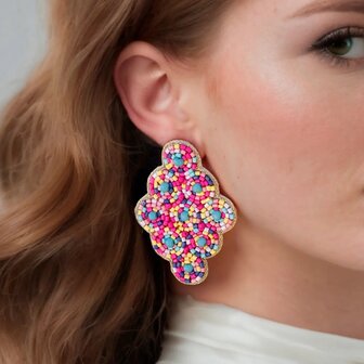 Persoon draagt gouden ruit oorbellen met kraaltjes 7 cm lang