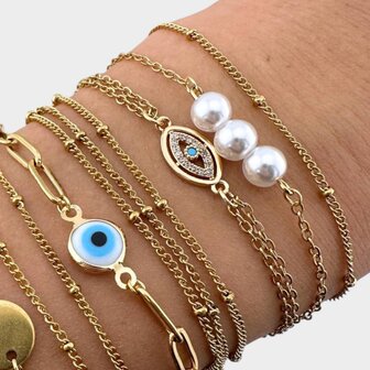 Persoon draagt duo armbanden met witte parel en steentje samen met andere armbanden